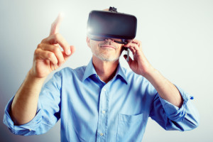 A satisfied mature business man wears a virtual reality headset, controlling the experience with hand gestures, while talking on a mobile/cell phone.